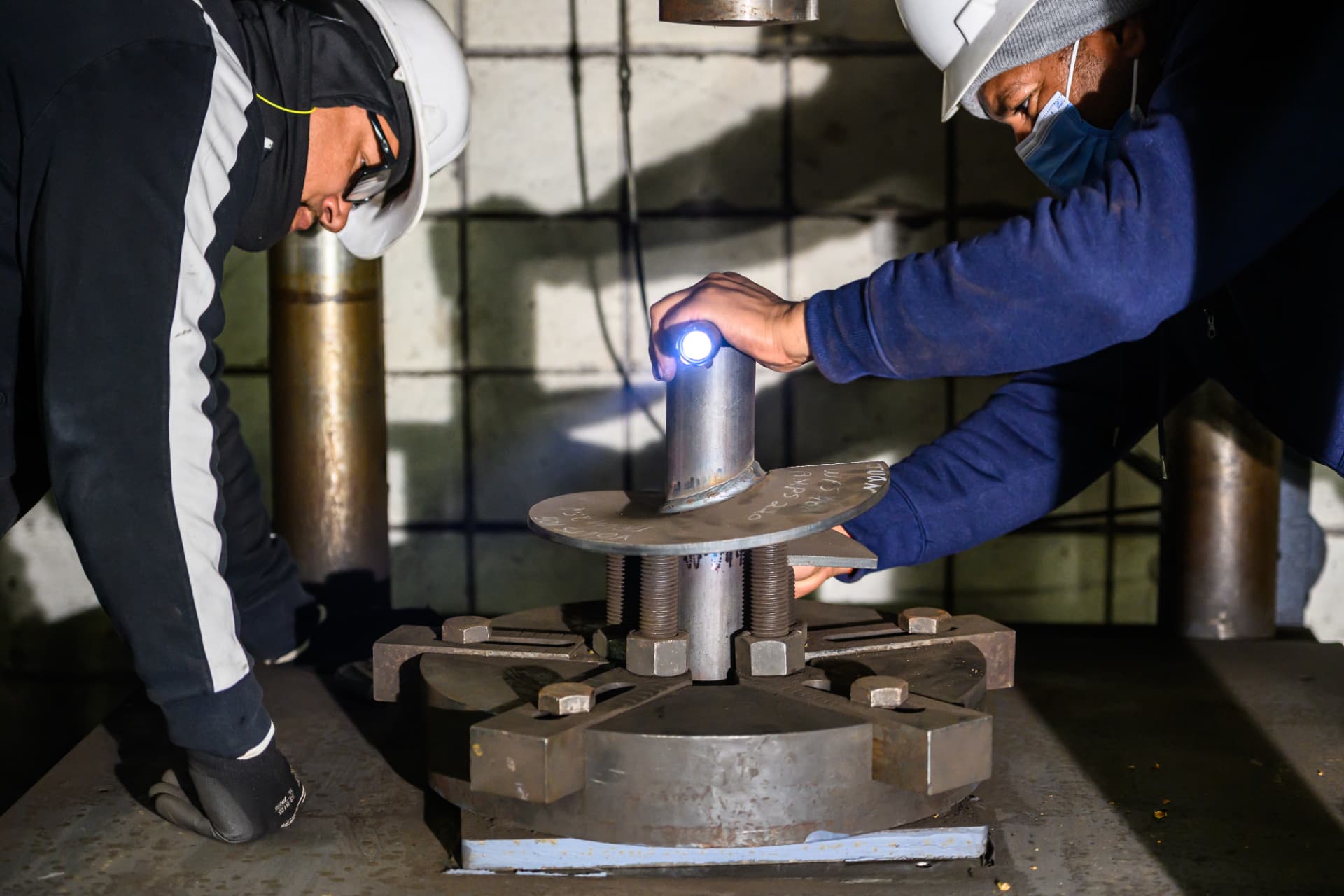 Technicians inspecting a helix weld on a test fixture