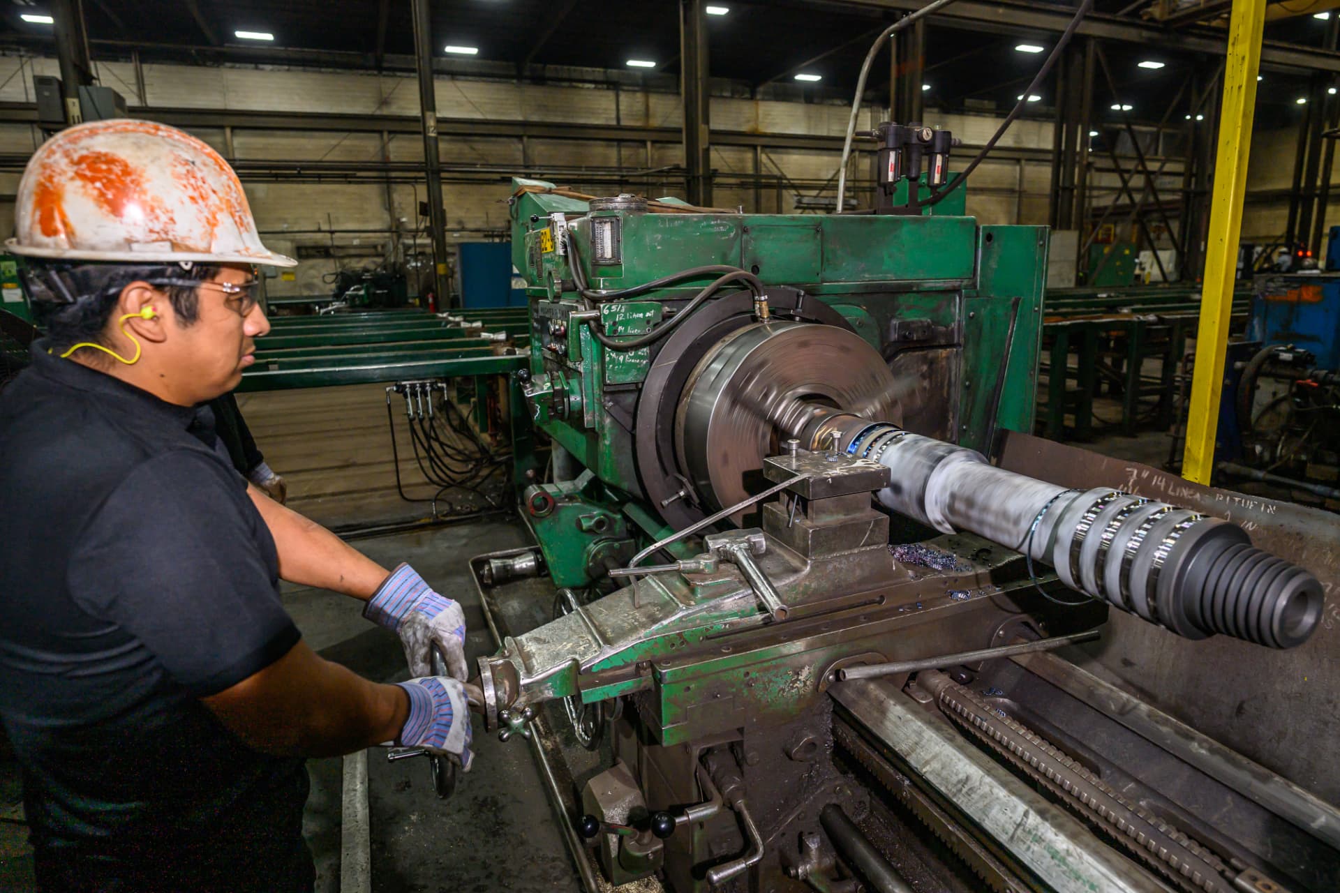 Lathe operator machining a threaded helical pile shaft