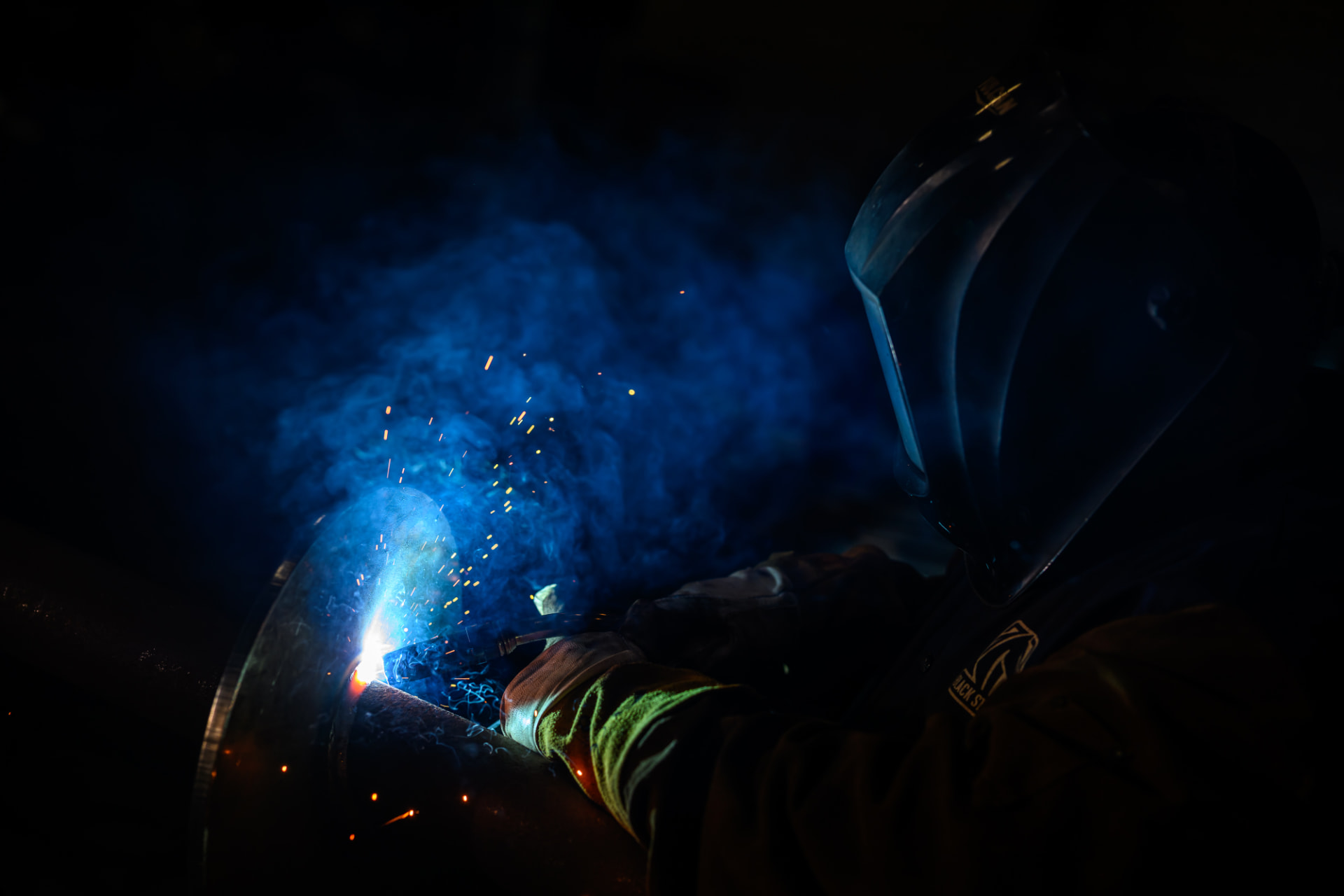 Welder joining steel foundation components under arc light